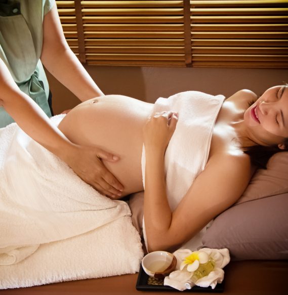 The pregnant woman laying down on bed was massage by Therapist hands,for treatment and relax pregram,blurry light around